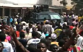 A screen grab taken from a video released by TVC News shows police forces patrolling while residents react after earlier bomb blasts in Maiduguri on 25 November 2014.