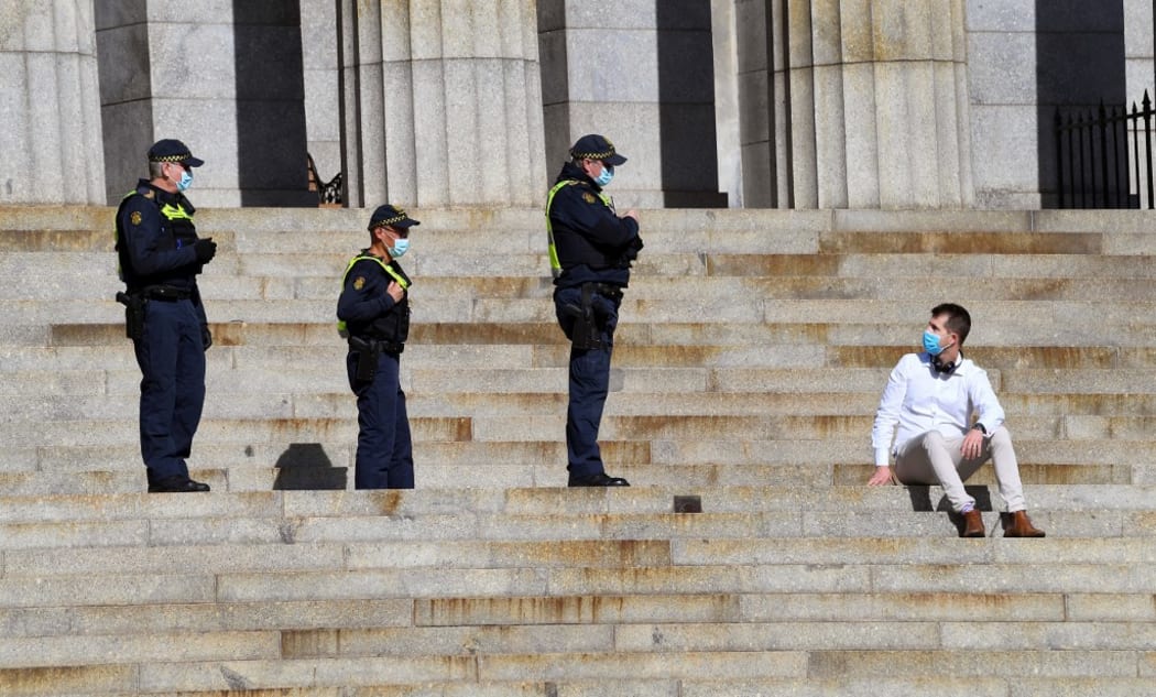 Protective Services officers speak to a man sitting on the steps of the Shrine of Remembrance in Melbourne on July 31, 2020.