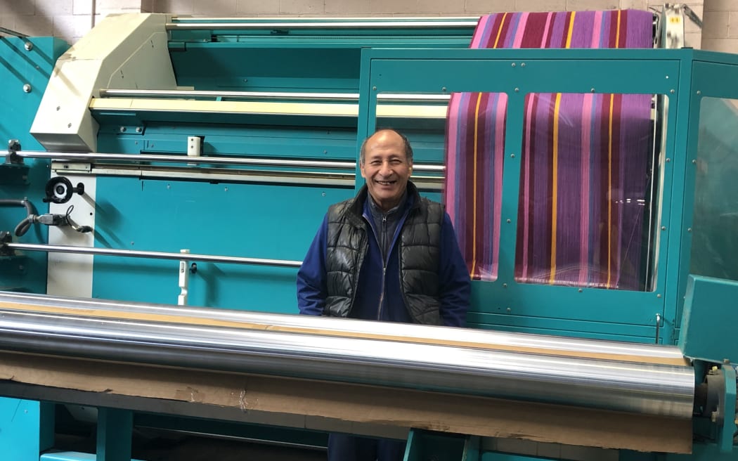 A man standing next to a weaving machine.