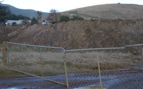 The quarried dirt 'overburden' dumped in large piles in front of the quarry pit.