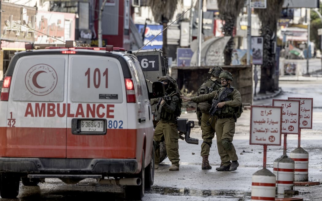 Israeli soldiers control a Palstinian ambulance leaving the Jenin refugee camp, in Jenin, on December 13, 2023, amid ongoing battles between Israel and the Palestinian movement Hamas.