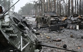 Ukrainian servicemen walk next to destroyed Russian tanks and armored personnel carriers in Dmytrivka village, west of Kyiv, on 2 April, 2022.