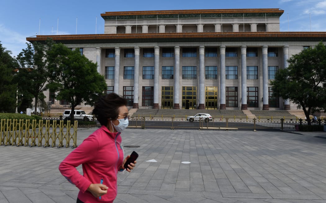 A woman runs past the Great Hall of the People, the venue for the annual meeting of the National People's Congress, China's rubber-stamp legislature in Beijing on May 20, 2020. -