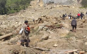 People dig through mud and rocks on 28 May, 2024, after a major landslide in Yambali village in Enga province, Papua New Guinea.