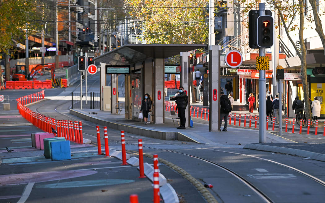 People wait for a tram in the empty central business district in Sydney on June 27, 2021, on the first full day of a two-week Covid-19 coronavirus lockdown to contain an outbreak of the highly contagious Delta variant.