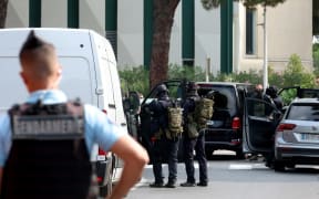 Law enforcement officers stand in front of a synagogue, in background on the right on the photo, following the fire and explosion of cars in La Grande-Motte, south of France, on August 24, 2024. At least two cars, one containing a gas bottle, were set alight on the morning of August 24, 2024, in front of the synagogue in La Grande-Motte, causing an explosion that injured a local policeman, the French gendarmerie and the town's mayor said. (Photo by Pascal GUYOT / AFP)