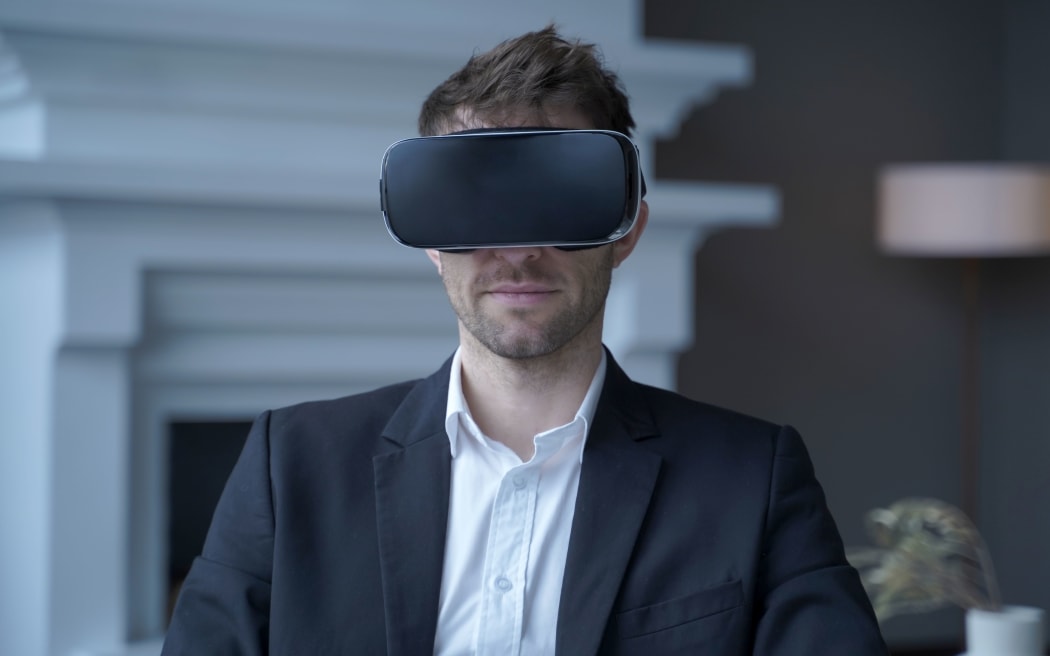 Serious businessman in black suit in VR headset on head working on project in augmented reality in office, male entrepreneur using innovative virtual reality glasses for work. 3d visualization concept