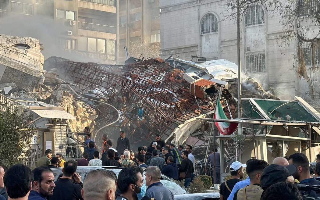 Emergency and security personnel gather at the site of strikes which hit a building next to the Iranian embassy in Syria's capital Damascus, on April 1, 2024. Syrian state media said Israeli strikes hit an Iranian consulate annex in the capital on April 1, while a war monitor reported eight people were killed and Iranian state media said a senior commander of the powerful Islamic Revolutionary Guard Corps was among the dead, amid rising regional tensions due to the Gaza war. (Photo by Maher AL MOUNES / AFP)