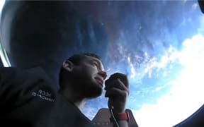 This September 16, 2021, image courtesy of Inspiration4 shows the Inspiration4 crew member Jared Isaacman communicating while looking out of an observation window while in orbit.
