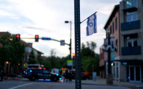 An Israeli flag is seen on a street sign in Boulder City, as police can be seen near Pearl Street, the scene of an attack on demonstrators on 1 June, 20205 as they called for hostages held in Gaza to be released.