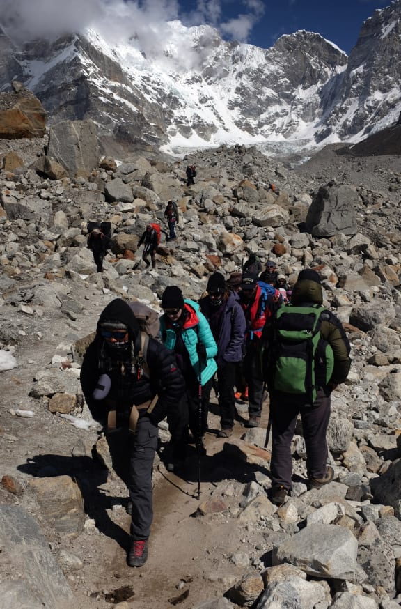Trekkers and climbers make their way up and down a trail leading to Everest Base Camp on 24 April, 2015.