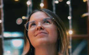 Laura looks up at twinkling lights. She smiles.