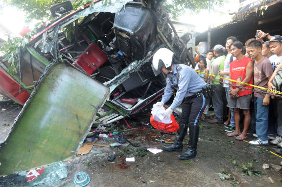 An officer collects at the scene of a bus crash in Manila in which at least 21 people died.