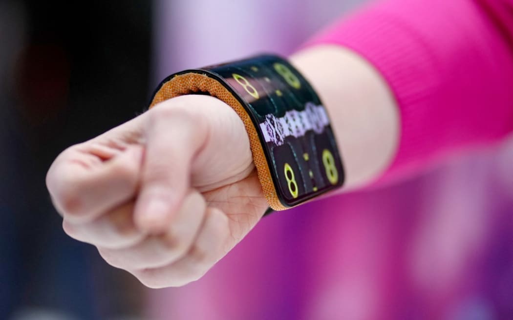 A model presents a Motorola prototype with an adaptive display used as bracelet during the Mobile World Congress (MWC), the telecom industry's biggest annual gathering, in Barcelona on February 27, 2024. The world's biggest mobile phone fair throws open its doors in Barcelona with the sector looking to artificial intelligence to try and reverse declining sales. (Photo by PAU BARRENA / AFP)