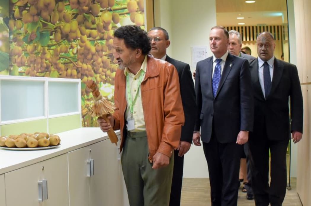 Prime Minister John Key takes part in the Maori blessing of the Singapore office, led by carver James Tapiata (left).