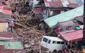 Vehicles are seen amongst the debris swept away by flash flood at the height of Typhoon Kalmaegi, along a street of a village in La Carlota city, Negros Oriental province, central Philippines