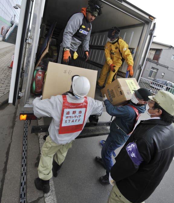 Photo taken on March 25, 2011 shows former New Zealand All Black Pita Alatini (top R) and a member of the Seawaves rugby club unloading emergency suppies from a truck in Kamaishi, a port town in northeastern Japan that devastated by the March 2011 tsunami.