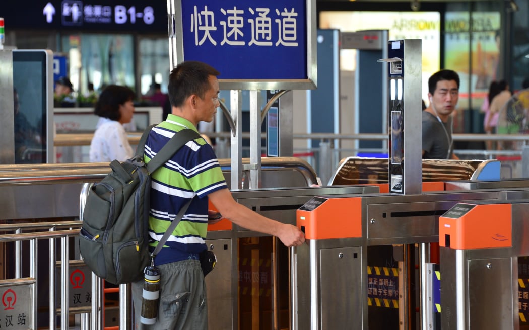 A passenger scans his face after having his train ticket automatically scanned for check-in at the Wuhan Railway Station in Wuhan city, central China's Hubei province, 21 August 2017.
