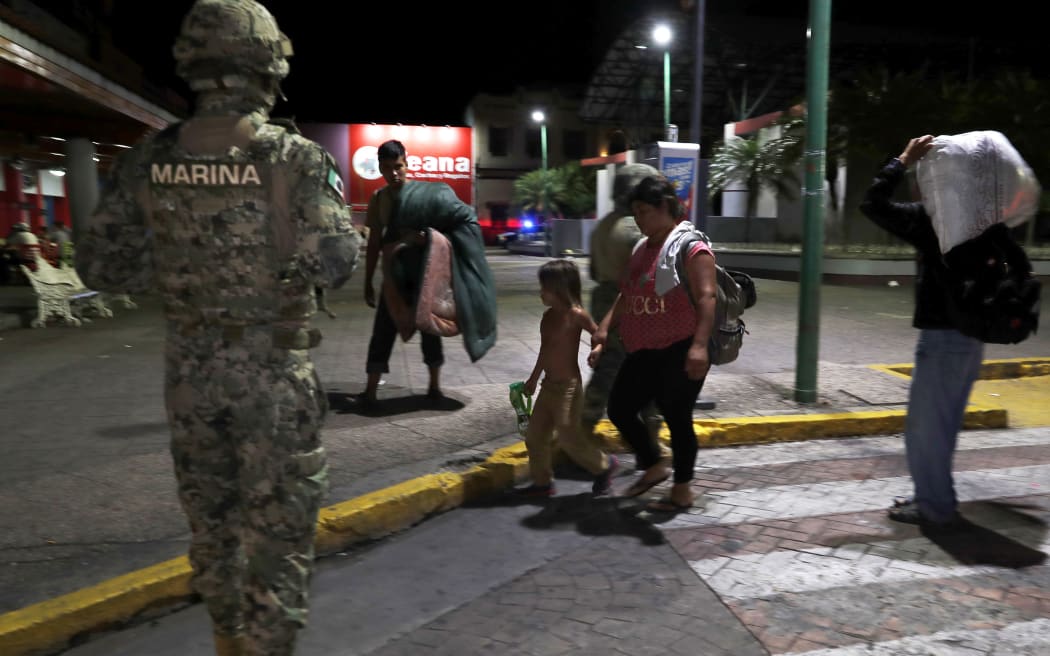 A Mexican marine stands by as camping migrant families are evicted from a park in Tapachula, Mexico, early Wednesday, May 29, 2019.