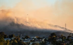 A helicopter fighting the Port Hills fire on 14 February 2024 as seen from the Christchurch suburb of Somerfield.