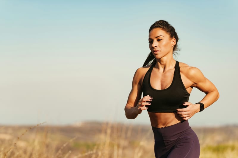 Woman running in sports bra outdoors.