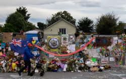 A man man walks past flowers and tributes displayed in memory of the twin mosque massacre victims along the road outside the Linwood mosque (back C) in Christchurch on March 25, 2019. The slaughter of 50 people at Friday prayers in two Christchurch mosques on March 15 shocked the normally laid-back country and prompted global horror, heightened by the gunman’s cold-blooded livestreaming of the massacre. (Photo by ANTHONY WALLACE / AFP)