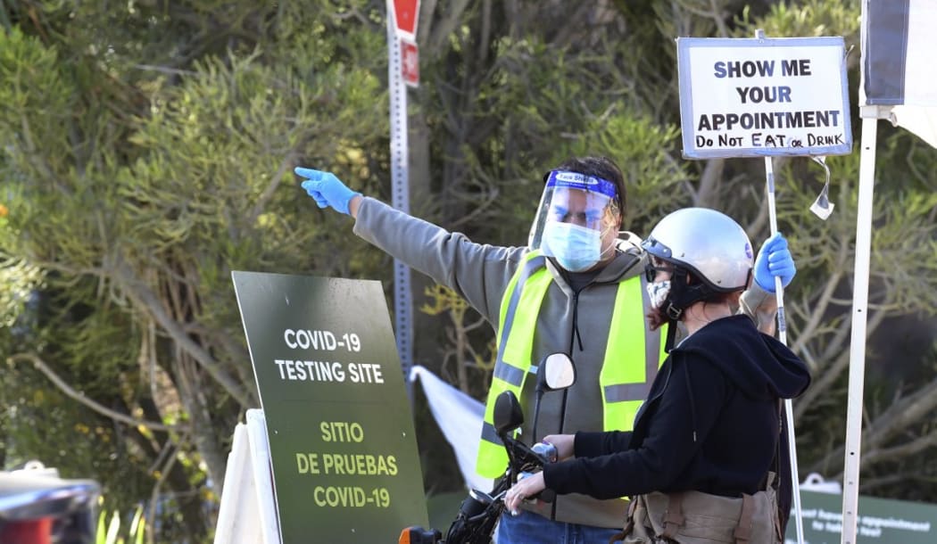 A volunteer gives directions as people arrive and depart from the Covid-19 testing venue at Dodger Stadium in Los Angeles, California on November 12, 2020. -