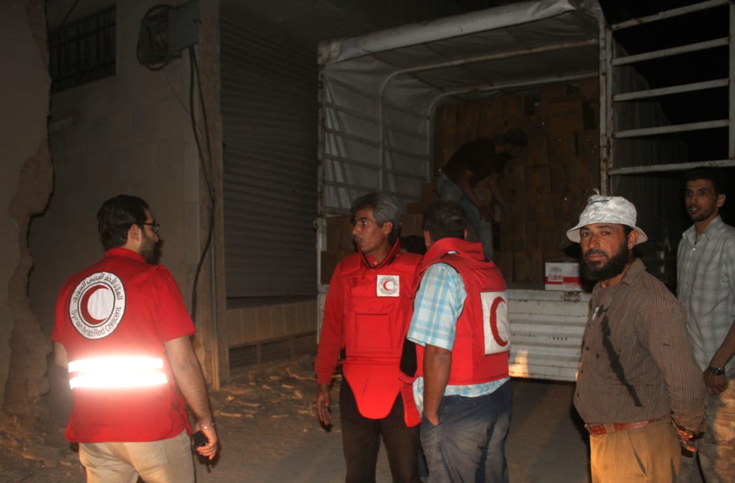 Members of the Syrian Arab Red Crescent unload a lorry after a UN and SARC aid convoy entered the Syrian rebel-held town of ‪Daraya