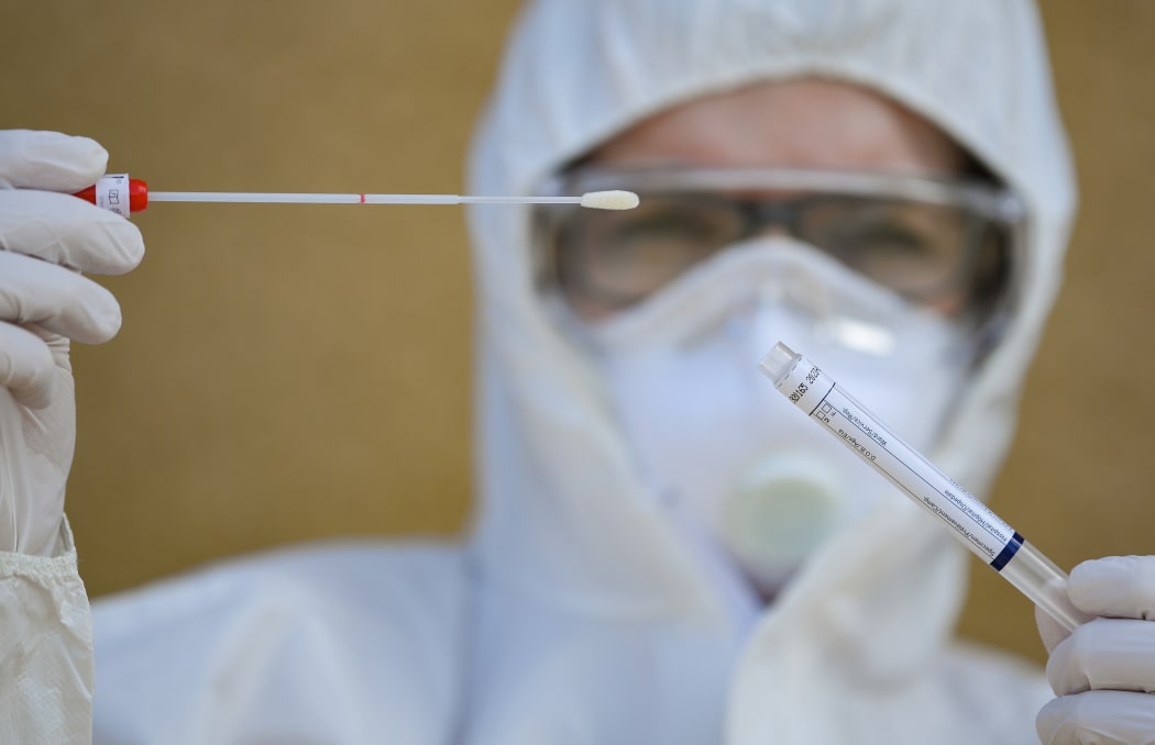 A medical assistant in protective equipment holds a test for the coronavirus Sars-Cov-2 in her hands.