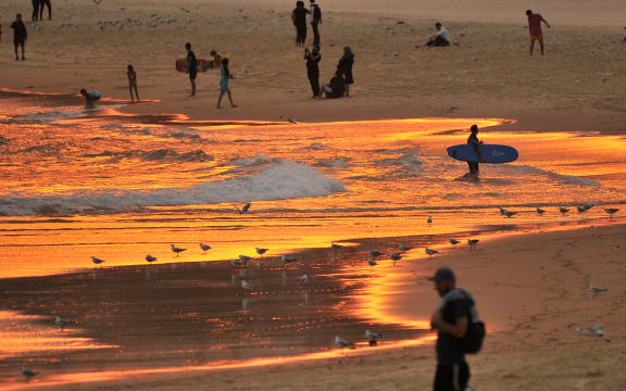 Beachgoers enjoy the sunset at Bondi beach during a heatwave in Sydney on December 19, 2019. A state of emergency was declared in Australia's most populated region on December 19 as an unprecedented heatwave fanned out-of-control bushfires, destroying homes and smothering huge areas with a toxic smoke. (Photo by FAROOQ KHAN / AFP)