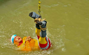 In this photo taken on June 16, 2019 Indian stuntman Chanchal Lahiri, known by his stage name "Jadugar Mandrake", is lowered into the Ganges river, while tied up with steel chains and ropes, in Kolkata.