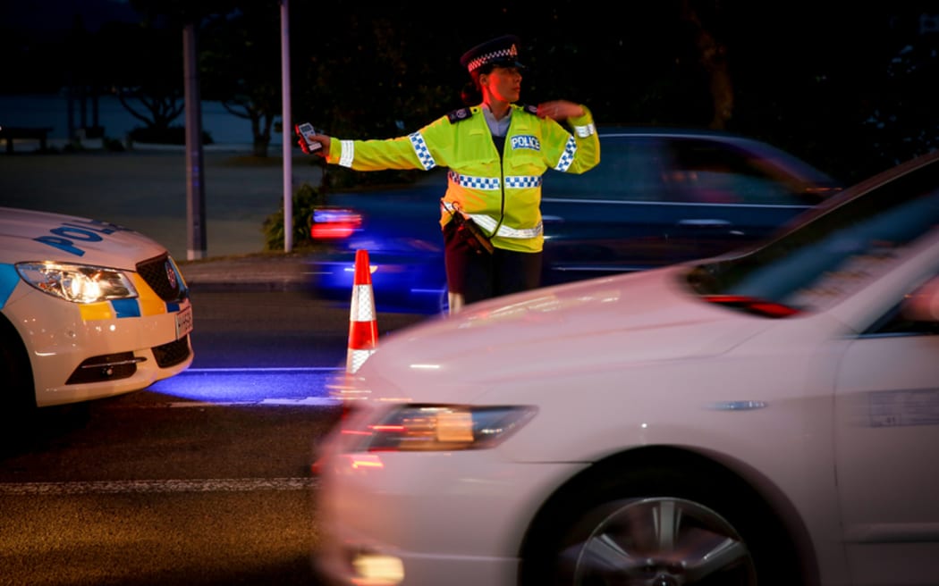 A police officer directing traffic at a alcohol check point.