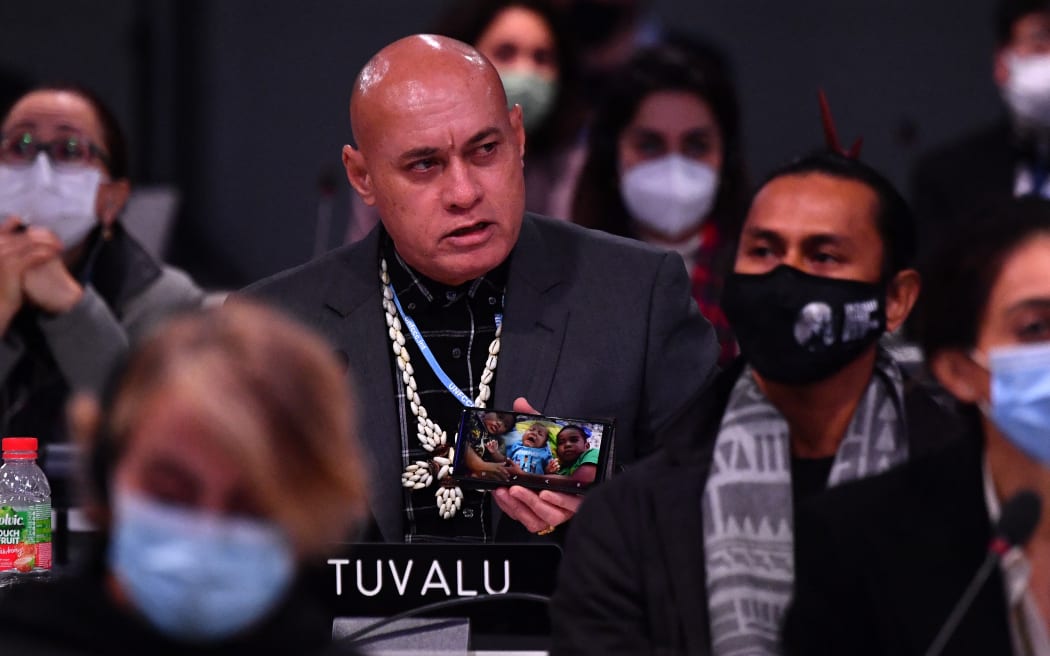 Tuvalu's Finance Minister Seve Paeniu shows a photo of his grandchildren as he speaks during an intervention at an informal plenary during the COP26 UN Climate Change Conference in Glasgow on November 13, 2021.
