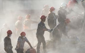 Search and rescue volunteers search the rubble of a collapsed building for survivors on October 31, 2020, in Izmir, after a powerful earthquake struck Turkey's western coast and parts of Greece.