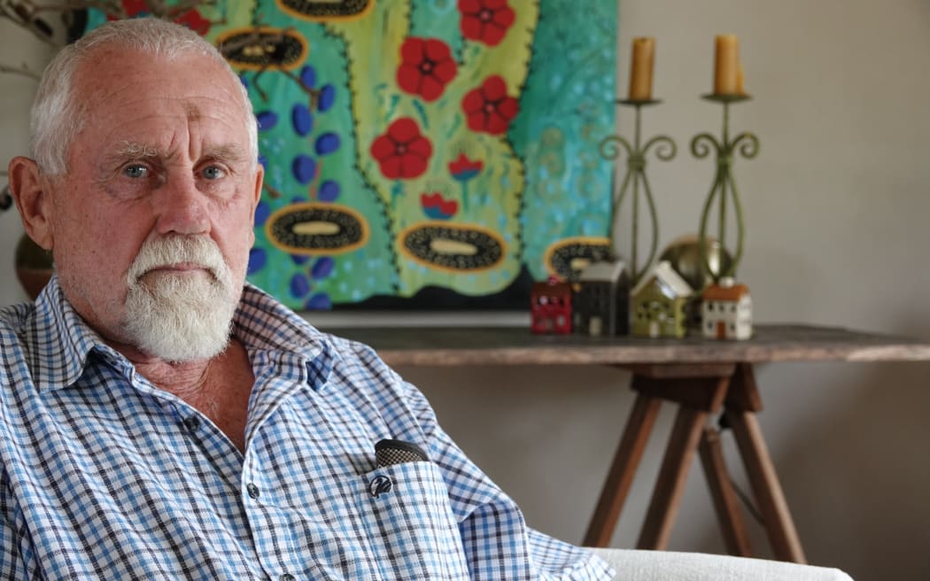 Garry Spence sit in front of one of his wife Liz's artworks, which was saved from their Pakowhai property.
