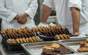 Chef finishing baked cookies in commercial stainless steel kitchen