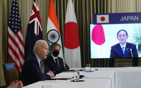 (L-R) U.S. President Joe Biden, U.S. Secretary of State Anthony Blinken and Japanese Prime Minister Yoshihide Suga (on screen) participate in a virtual meeting with leaders of The Quad.