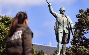 People walk past a statue of Captain James Cook in Sydney's Hyde Park on August 25, 2017,