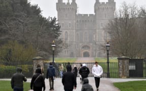 People walk up to the gates of Windsor Castle, the main residence of Britain's Queen Elizabeth II, on 20 February. The Queen tested positive for Covid-19 a fortnight after marking 70 years on the throne.