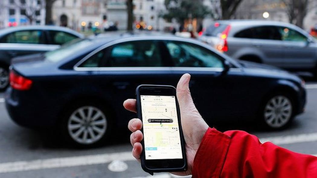 An UBER application is shown as cars drive by in Washington, DC