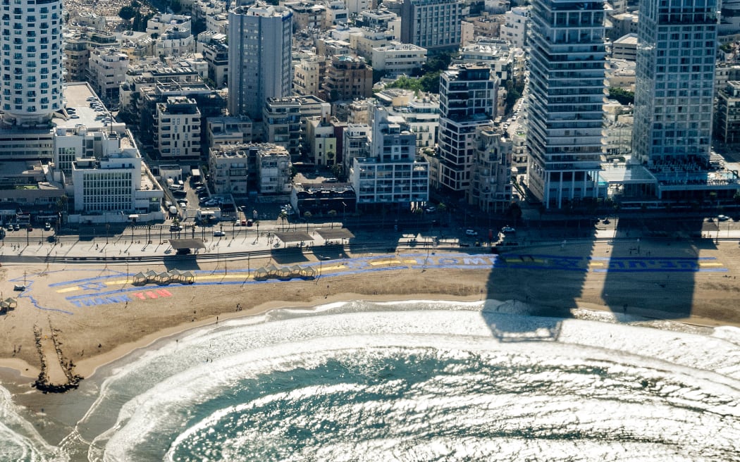 TOPSHOT - This picture taken in flight from aboard Air Force One shows a message of "Thank you" displayed on the beach outside the US embassy headquarters in Tel Aviv, prior to US President Donald Trump's landing at Ben Gurion Airport on October 13, 2025, as he travels to Israel and Egypt. Trump is passing through Israel, addressing parliament and meeting with hostage families before heading to Egypt's Sharm El-Sheikh for a major peace summit, where a "document ending the war in the Gaza Strip" is expected to be signed. (Photo by SAUL LOEB / AFP)