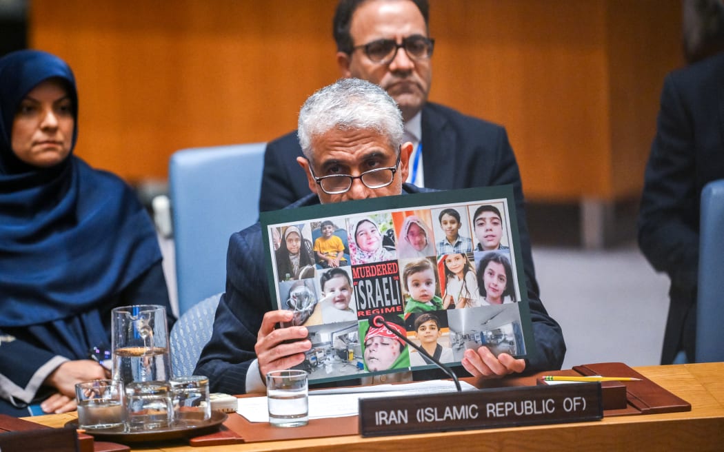 Iran's UN representative Amir Saeid Iravani displays photos as he speaks during a United Nations Security Council meeting on the Israel-Iran conflict at the UN headquarters in New York on June 20, 2025. The head of the UN nuclear watchdog pleaded on June 20 for a diplomatic solution to end Israel's strikes on Iran, saying his agency could guarantee strict monitoring in any deal on putting Iranian nuclear technology under international control. (Photo by ANGELA WEISS / AFP)