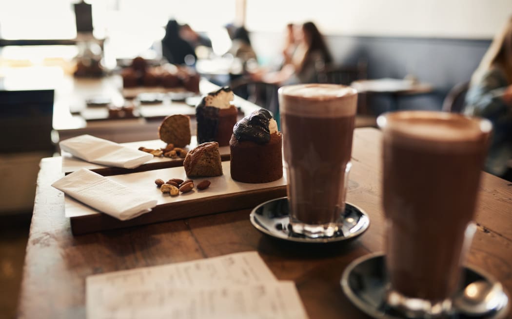 Closeup of an assortment of delicious chocolate desserts sitting with drinks on a serving counter in a bakery