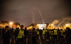 "Yellow vests" demonstrators wave Breton and French flags in front of the Arc de Triomphe, which was completely destroyed inside.