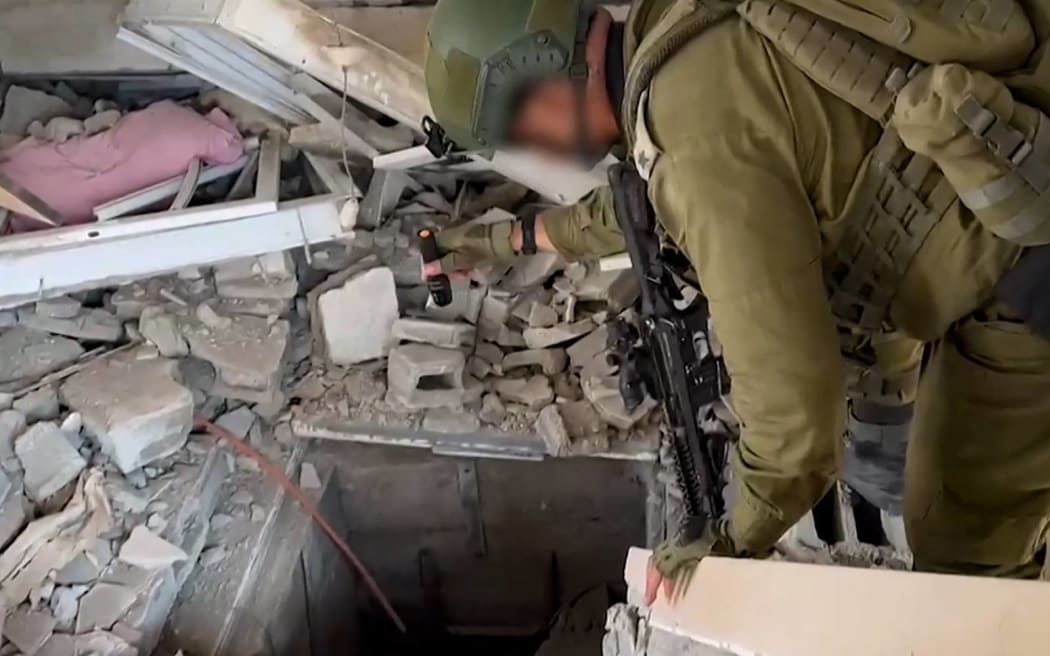 This screen grab taken from a handout footage released by the Israeli army on November 3, 2023, shows an Israeli soldier checking what it says is the entrance to a tunnel used by the Palestinian Hamas movement in the Gaza Strip, as battles between Israeli forces and Hamas continue. (Photo by Israeli Army / AFP) / RESTRICTED TO EDITORIAL USE - MANDATORY CREDIT "AFP PHOTO / ISRAELI ARMY  " - NO MARKETING NO ADVERTISING CAMPAIGNS - DISTRIBUTED AS A SERVICE TO CLIENTS