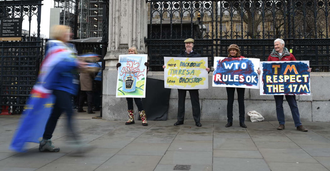 Pro-Brexit supporters outside the Houses of Parliament as an anti-Brexit campaigner walks by in central London.