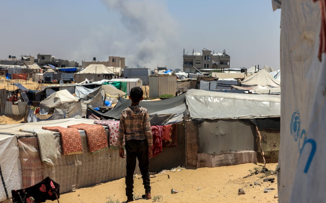 A Palestinian child looks on as smoke billows in the distance during Israeli bombardment in Rafah, in the southern Gaza Strip on June 11, 2025. (Photo by AFP)