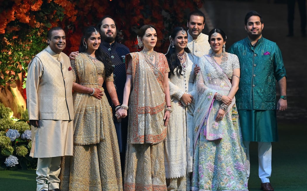 Indian billionaire Mukesh Ambani (L) along with his wife Nita (4L) pose with their elder son Akash (R) his wife Shloka (2R), daughter Isha (4R) her husband Anand Piramal (3R) and younger son Anant (3L) his fiancée Radhika Merchant (2L) during Anant's engagement ceremony in Mumbai on January 19, 2023. (Photo by Sujit JAISWAL / AFP)