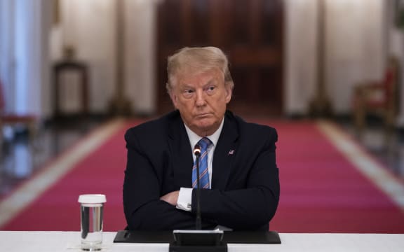 US President Donald Trump sits with his arms crossed during a roundtable discussion on the Safe Reopening of Americas Schools during the coronavirus pandemic, in the East Room of the White House on July 7, 2020, in Washington, DC. (Photo by JIM WATSON / AFP)