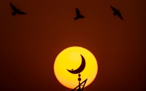 The sun sets behind the mosque outside the Khalifa Stadium in Doha, Qatar.
